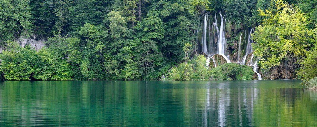 Spring waterfall in Plitvicka Jezera, Croatia, flowing through lush forest, perfect for murals.